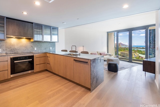 1000 Auahi St Unit 1404, Honolulu, HI 96814 - kitchen featuring modern cabinets, tasteful backsplash, a sink, light wood-style flooring, and black appliances