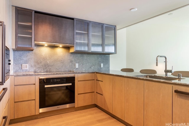 1000 Auahi St Unit 1404, Honolulu, HI 96814 - kitchen with light stone countertops, a sink, light wood finished floors, backsplash, and black appliances