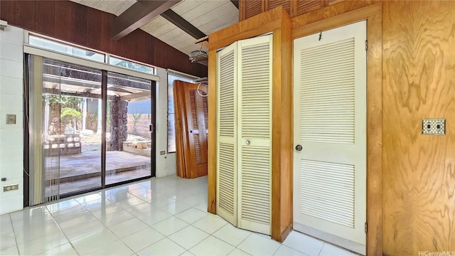 interior space featuring light tile patterned floors and vaulted ceiling with beams