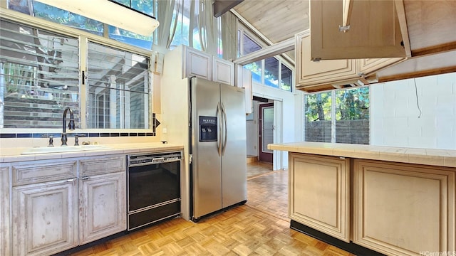 kitchen with stainless steel refrigerator with ice dispenser, a sink, dishwasher, and tile counters
