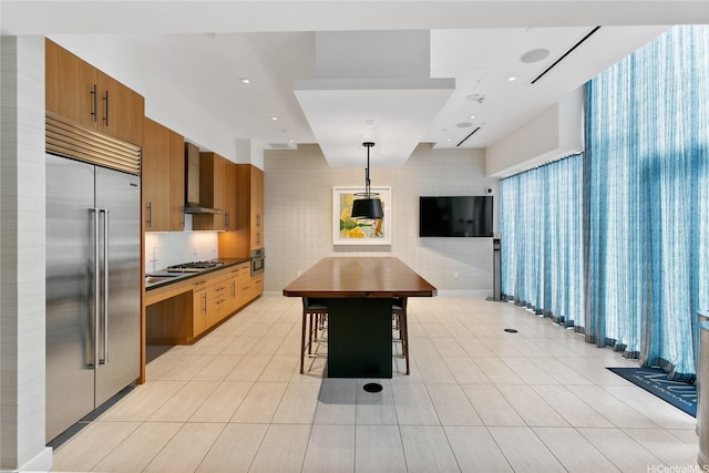 629 Keeaumoku St Unit 3401, Honolulu, HI 96814 - kitchen featuring wall chimney range hood, light tile patterned floors, stainless steel appliances, and brown cabinets