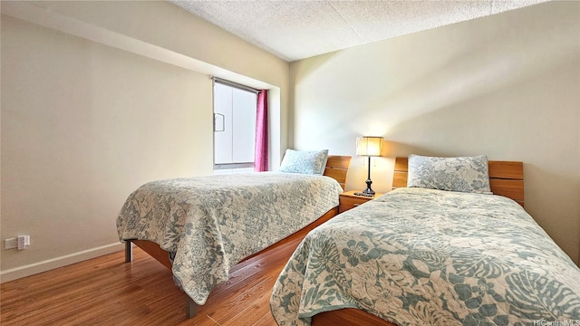 bedroom with baseboards, a textured ceiling, and wood finished floors
