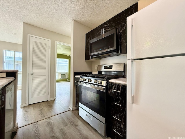 91-291 Hanapouli Cir Unit 4G, Ewa Beach, HI 96706 - kitchen featuring a textured ceiling, light wood-style flooring, a healthy amount of sunlight, and stainless steel appliances