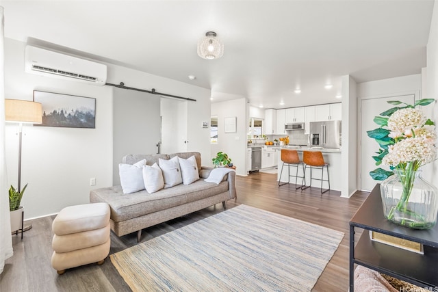 living area with wood finished floors, a barn door, a wall mounted AC, and recessed lighting