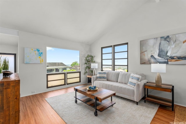 living room featuring baseboards, high vaulted ceiling, and wood finished floors