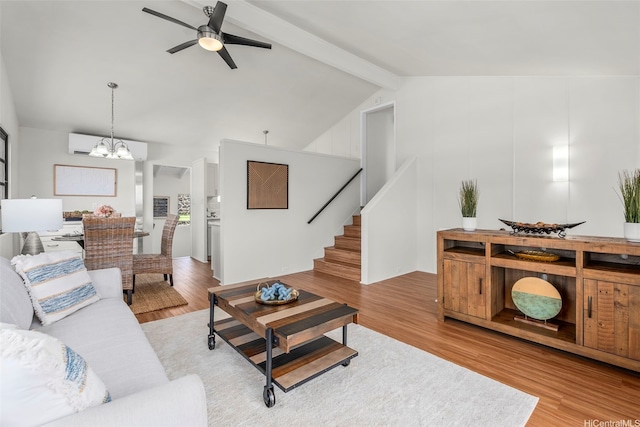 living room with light wood finished floors, ceiling fan with notable chandelier, stairs, vaulted ceiling with beams, and a wall mounted AC