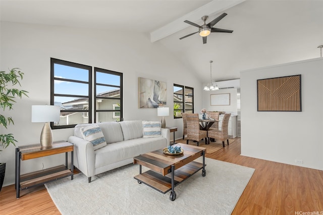living room with a wall unit AC, vaulted ceiling with beams, light wood finished floors, and ceiling fan with notable chandelier