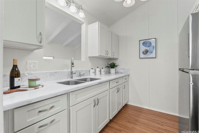 kitchen featuring a sink, white cabinetry, freestanding refrigerator, and light countertops