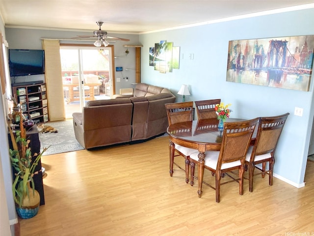 dining space with crown molding, a ceiling fan, and light wood-style flooring