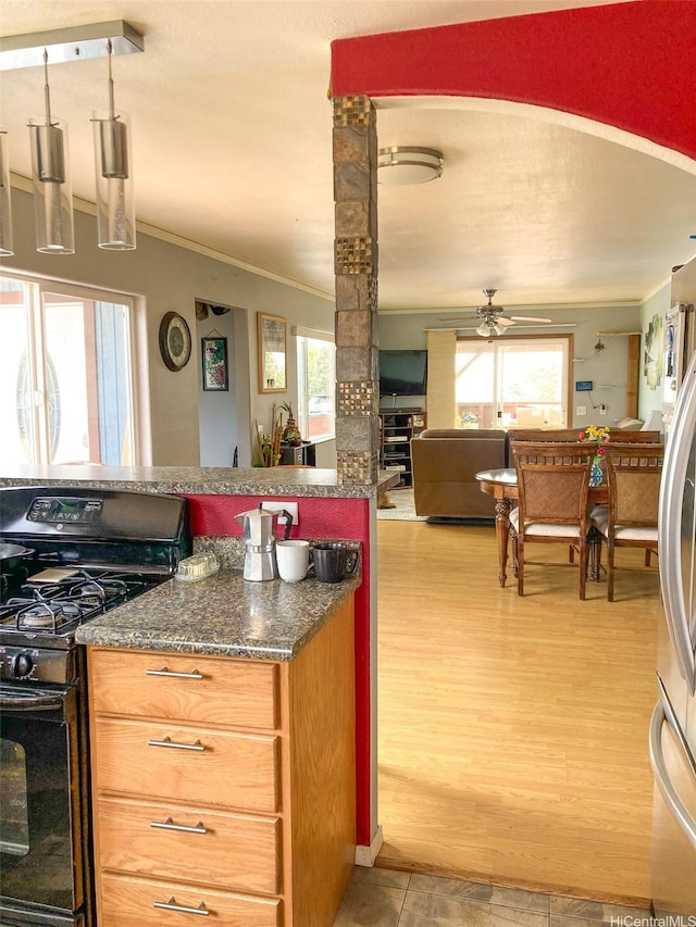 kitchen featuring gas stove, light wood-style floors, a ceiling fan, open floor plan, and ornamental molding