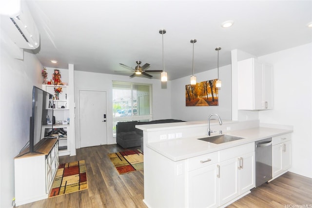 kitchen with a wall mounted AC, wood finished floors, dishwasher, a sink, and white cabinets