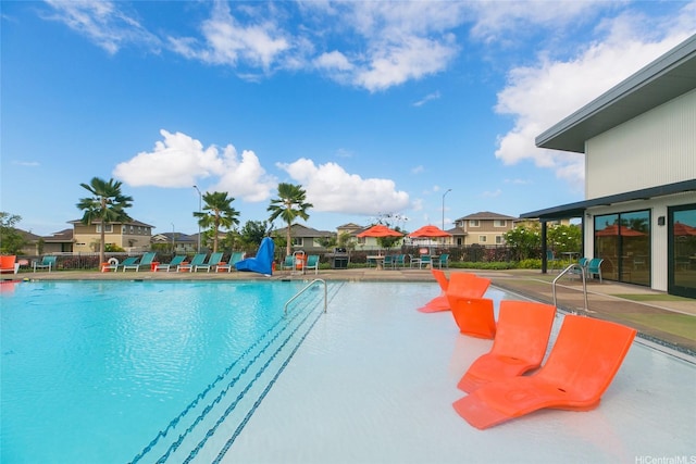 community pool featuring a patio area, fence, and a residential view
