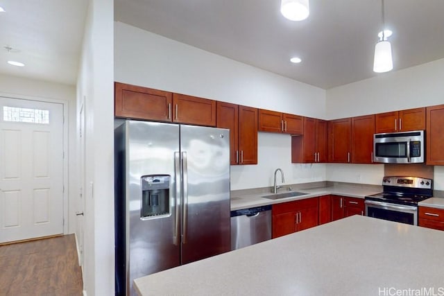 kitchen featuring wood finished floors, a sink, light countertops, appliances with stainless steel finishes, and recessed lighting