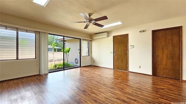 spare room with healthy amount of natural light, a wall mounted air conditioner, wood finished floors, a ceiling fan, and a textured ceiling