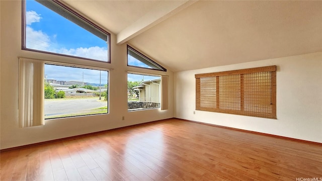 spare room with beamed ceiling, wood finished floors, baseboards, and high vaulted ceiling