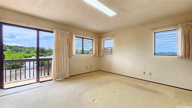 empty room featuring carpet, a textured ceiling, cooling unit, and baseboards