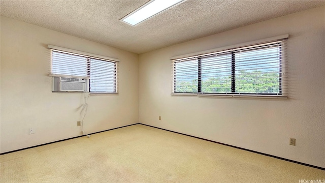 empty room featuring light colored carpet, cooling unit, a textured ceiling, and baseboards