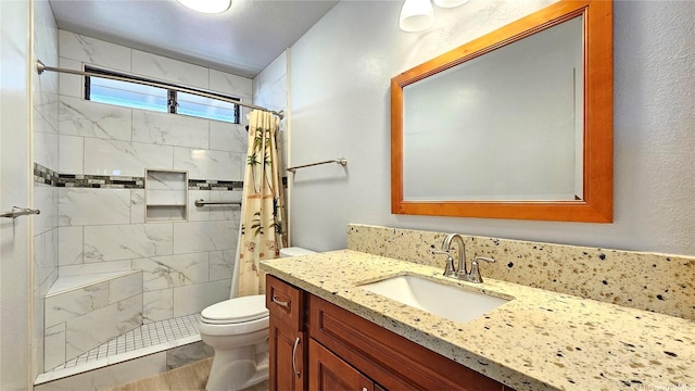 full bathroom featuring toilet, a tile shower, and vanity