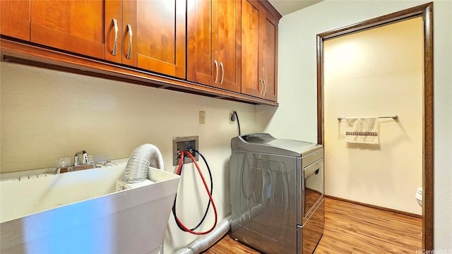 clothes washing area with cabinet space, hookup for an electric dryer, hookup for a washing machine, and light wood-style flooring