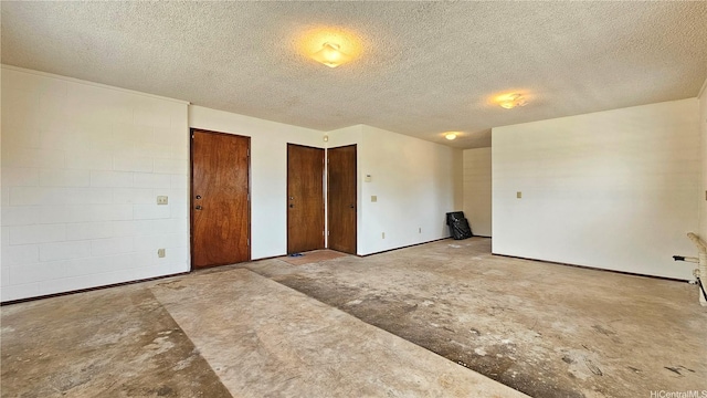 unfurnished bedroom with multiple closets, unfinished concrete flooring, and a textured ceiling