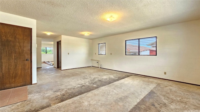 spare room with unfinished concrete flooring, healthy amount of natural light, and a textured ceiling