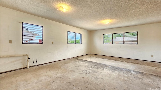 empty room with unfinished concrete flooring, concrete block wall, and a textured ceiling