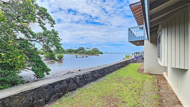 view of green lawn featuring a water view and a balcony