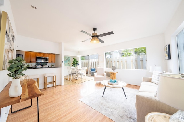 living area with a ceiling fan and light wood-style flooring