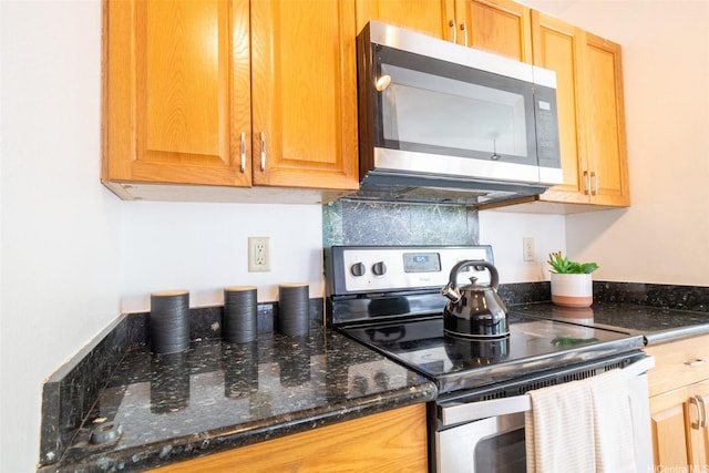 kitchen featuring appliances with stainless steel finishes and dark stone countertops
