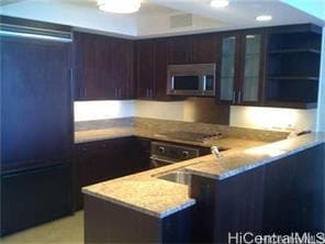 1551 Ala Wai Blvd Unit 1704, Honolulu, HI 96815 - kitchen featuring dark brown cabinetry, refrigerator, light stone counters, stainless steel microwave, and a peninsula