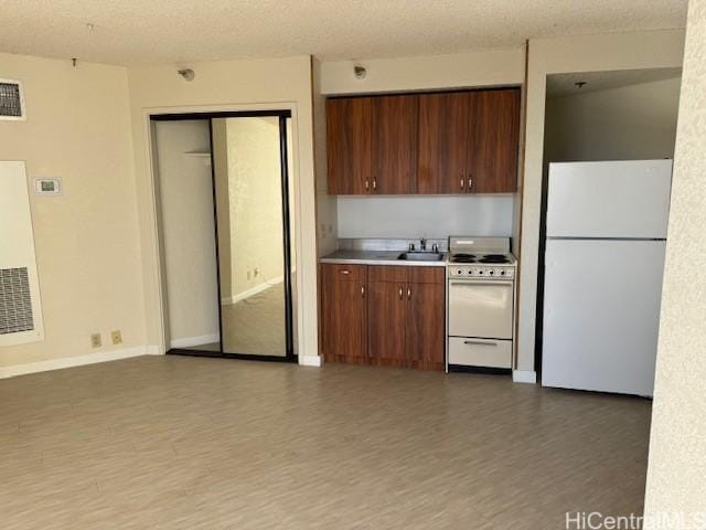 kitchen featuring wood finished floors, white appliances, baseboards, light countertops, and a sink