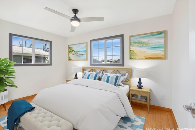 bedroom featuring a ceiling fan, baseboards, multiple windows, and wood finished floors