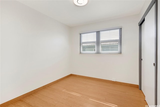 unfurnished bedroom with baseboards, light wood finished floors, and a closet
