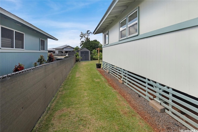 view of home's exterior featuring a storage shed, a lawn, fence, and an outbuilding