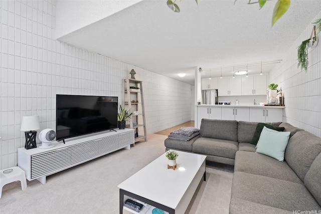 living area with tile walls, light carpet, and a textured ceiling