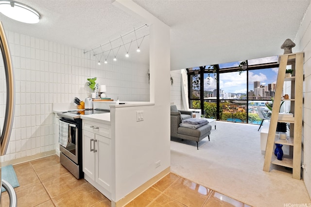 kitchen featuring light tile patterned floors, electric range, a textured ceiling, white cabinetry, and light countertops