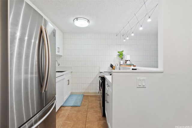 kitchen featuring freestanding refrigerator, tile walls, light tile patterned floors, light countertops, and white cabinets
