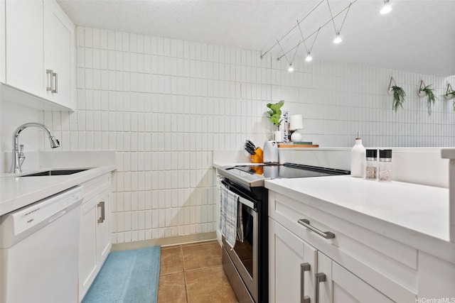 kitchen with a sink, tile walls, stainless steel electric range, and white dishwasher