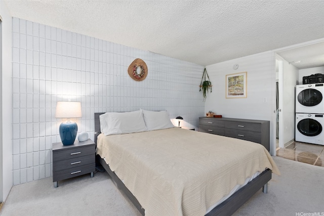 bedroom with a textured ceiling, light carpet, and stacked washer / drying machine