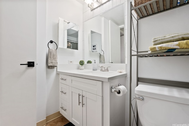bathroom with toilet, baseboards, and vanity
