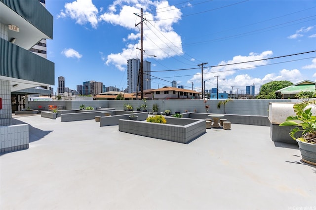 view of patio / terrace featuring a city view, a garden, and fence