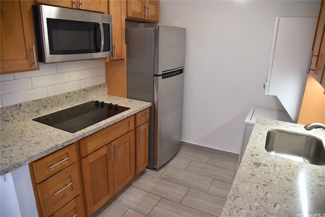 kitchen featuring a sink, backsplash, stainless steel appliances, and brown cabinetry