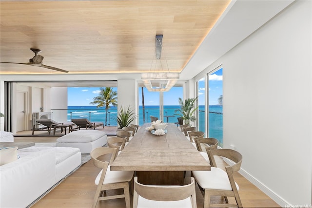 dining space with light wood-style floors, a ceiling fan, plenty of natural light, and a water view