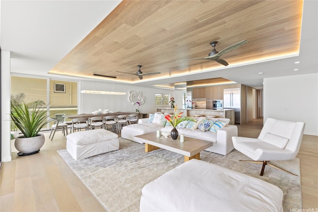 living room featuring light wood-style floors, wooden ceiling, ceiling fan, and a tray ceiling