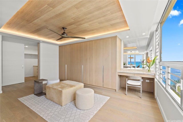 bedroom with multiple windows, wooden ceiling, light wood finished floors, and a raised ceiling