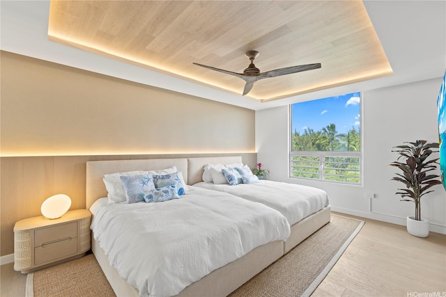 bedroom featuring a raised ceiling, wood ceiling, and light wood finished floors