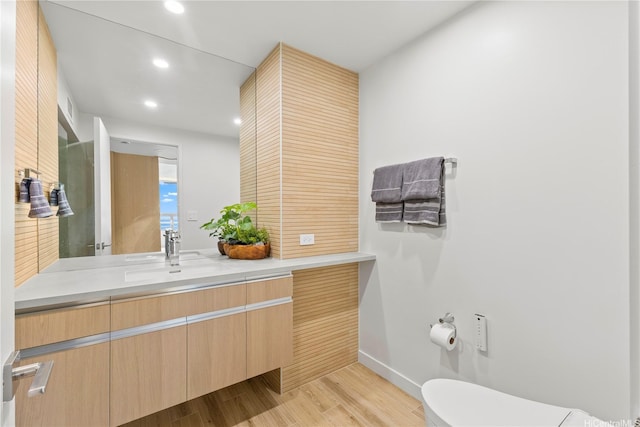 bathroom featuring wood finished floors, baseboards, vanity, toilet, and recessed lighting