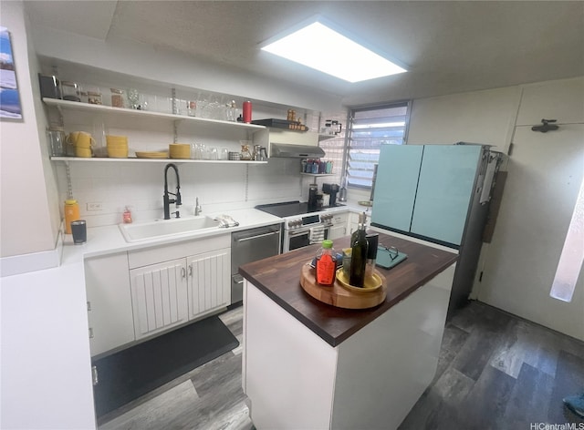 kitchen with open shelves, wood finished floors, white cabinets, a sink, and appliances with stainless steel finishes