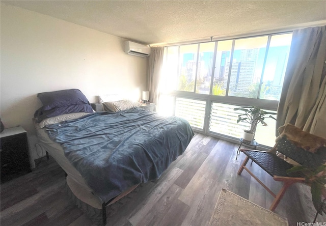 bedroom with a wall of windows, an AC wall unit, a textured ceiling, and wood finished floors