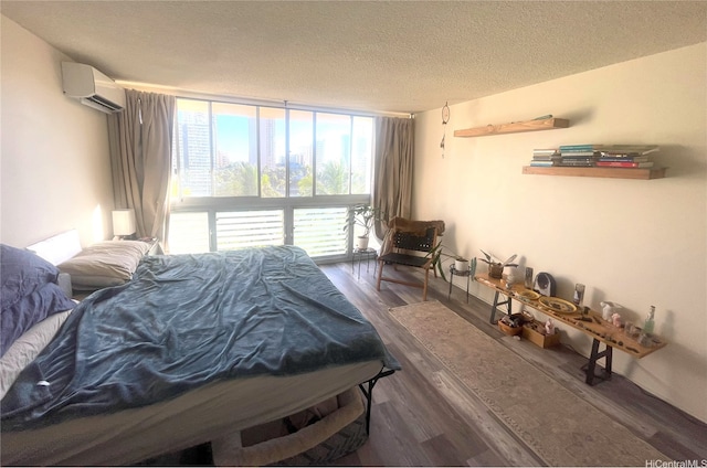 bedroom with a textured ceiling, floor to ceiling windows, a wall unit AC, and wood finished floors